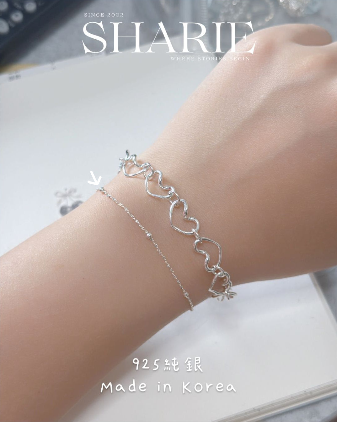 Silver bracelet on a wrist with 'SHARIE' branding and text indicating 'Made in Korea'.