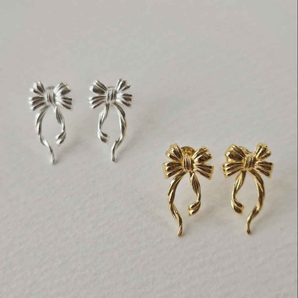 Discover the elegant E42 The Bow Earrings, crafted from premium 925 silver for a timeless shine. This Korea-inspired accessory features delicate bow motifs, perfect for everyday glamour or special occasions. Hypoallergenic, lightweight, and versatile—elevate your style with subtle sophistication. Ideal for fashion enthusiasts seeking affordable luxury.

#SilverEarrings, #925SterlingSilver, #SterlingSilverEarrings, #SilverJewelry, #HandmadeEarrings, #StatementEarrings, #EarringStyle, #MinimalistEarrings, #Fa