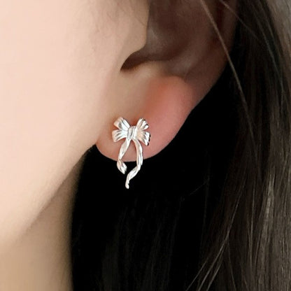 Discover the elegant E42 The Bow Earrings, crafted from premium 925 silver for a timeless shine. This Korea-inspired accessory features delicate bow motifs, perfect for everyday glamour or special occasions. Hypoallergenic, lightweight, and versatile—elevate your style with subtle sophistication. Ideal for fashion enthusiasts seeking affordable luxury.

#SilverEarrings, #925SterlingSilver, #SterlingSilverEarrings, #SilverJewelry, #HandmadeEarrings, #StatementEarrings, #EarringStyle, #MinimalistEarrings, #Fa